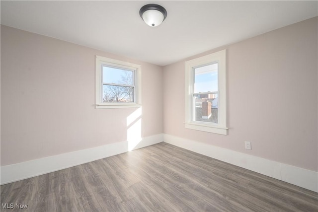 empty room with hardwood / wood-style floors and a healthy amount of sunlight