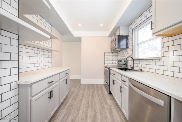 kitchen featuring white cabinetry, appliances with stainless steel finishes, light hardwood / wood-style floors, and decorative backsplash