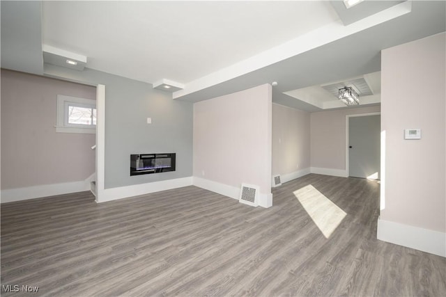 unfurnished living room featuring heating unit and hardwood / wood-style floors