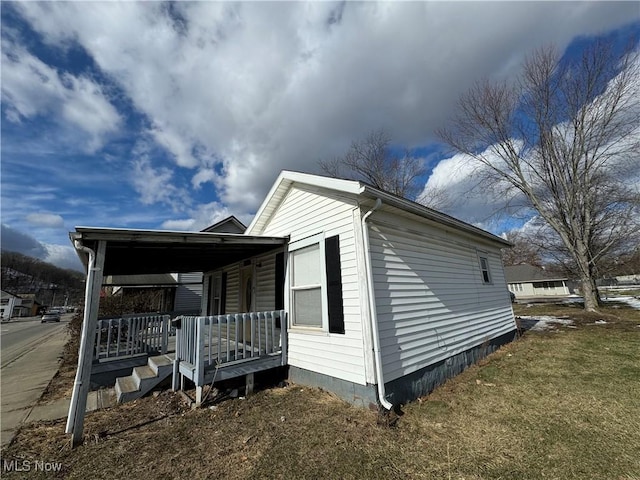 view of side of property featuring a yard and covered porch