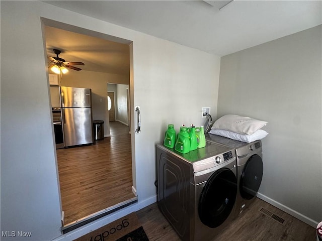 clothes washing area featuring ceiling fan, washing machine and clothes dryer, and dark hardwood / wood-style flooring