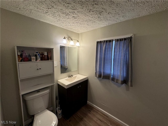 bathroom featuring vanity, a textured ceiling, wood-type flooring, and toilet