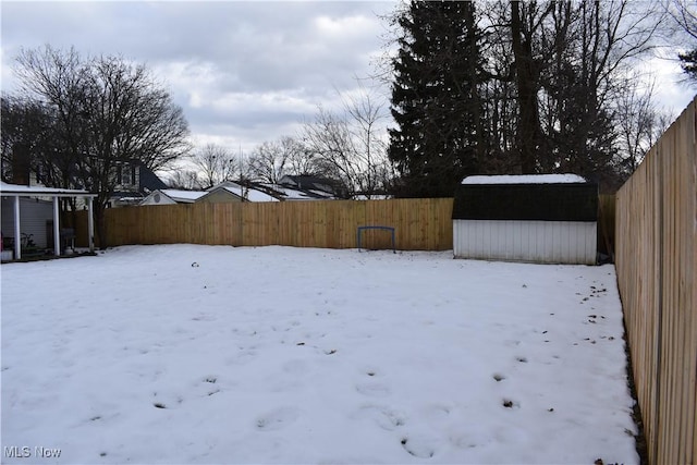 yard covered in snow featuring a storage shed