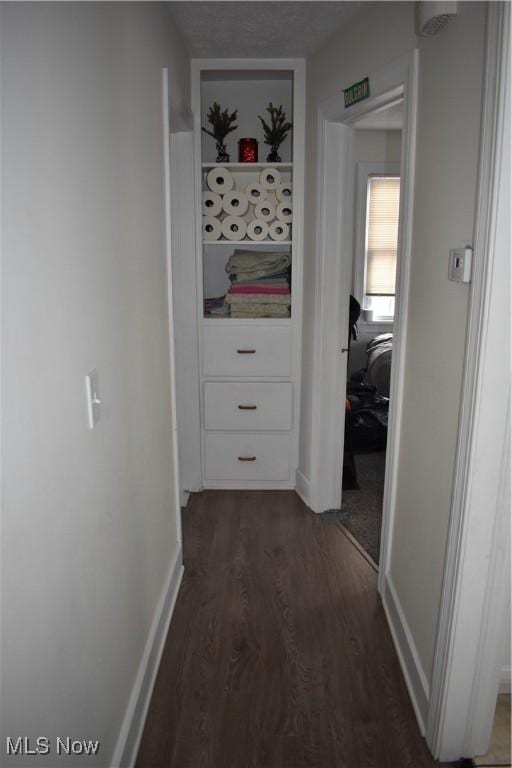 hall featuring dark wood-type flooring and baseboards