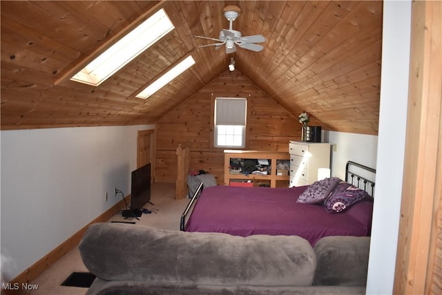 carpeted bedroom with ceiling fan, wooden ceiling, vaulted ceiling with skylight, and wood walls