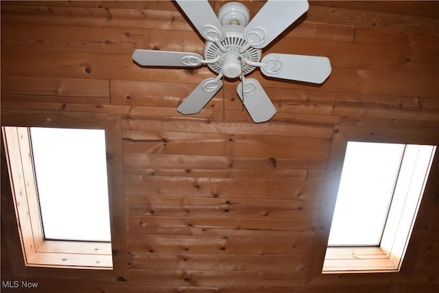 room details featuring ceiling fan and wood walls