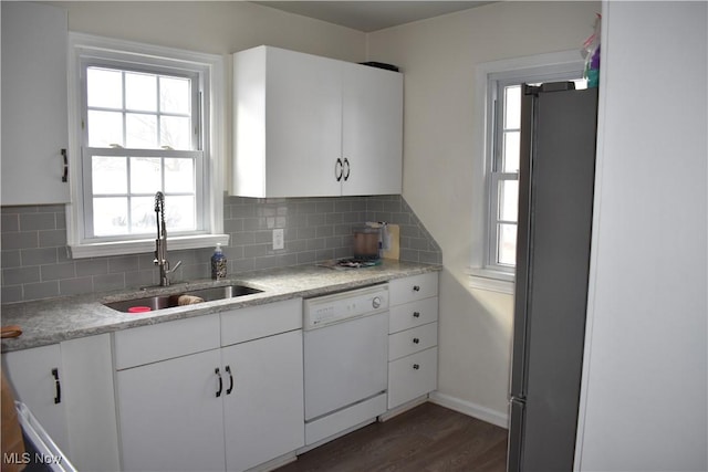 kitchen with tasteful backsplash, dishwasher, freestanding refrigerator, white cabinetry, and a sink