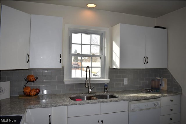 kitchen featuring dishwasher, backsplash, a sink, and white cabinetry