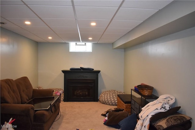 living area with a drop ceiling and light colored carpet