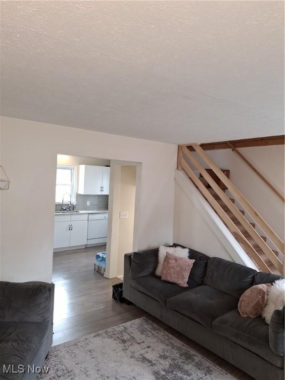 living room with a textured ceiling, stairway, and wood finished floors