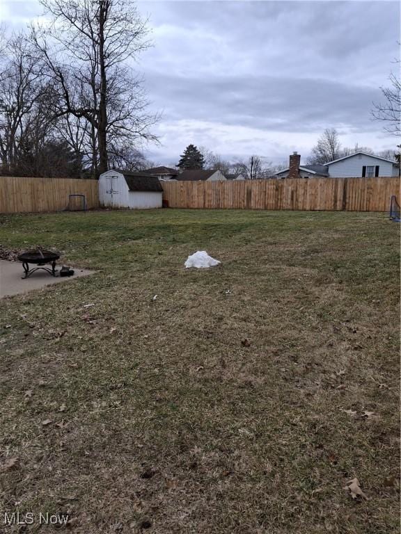 view of yard with a fire pit, a storage unit, an outbuilding, and fence private yard