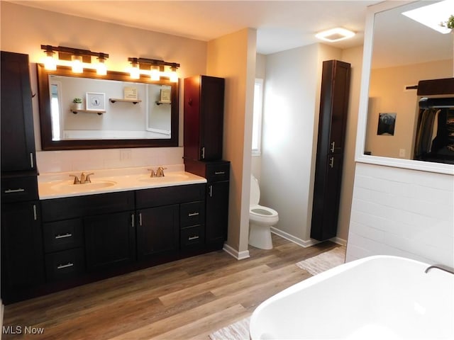 bathroom featuring vanity, toilet, hardwood / wood-style floors, and a tub