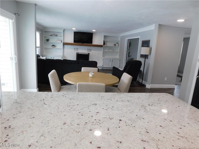 dining area featuring crown molding, built in features, and a fireplace