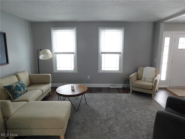 living room with a healthy amount of sunlight, dark wood-type flooring, and a textured ceiling