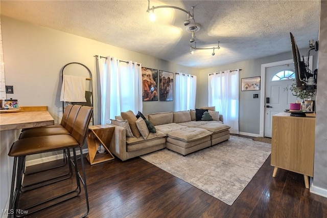 living room with track lighting, dark hardwood / wood-style flooring, and a textured ceiling