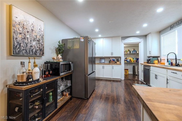 kitchen featuring butcher block countertops, sink, white cabinets, dark hardwood / wood-style flooring, and stainless steel appliances