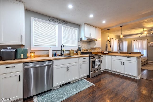 kitchen with appliances with stainless steel finishes, pendant lighting, white cabinetry, sink, and kitchen peninsula