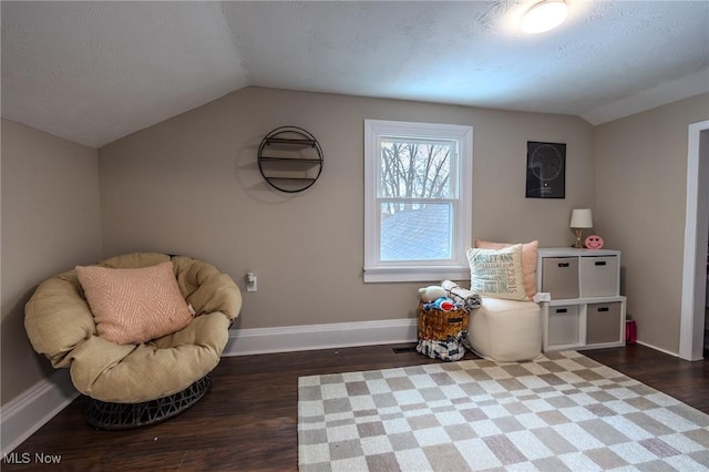 living area featuring dark wood-type flooring, vaulted ceiling, and a textured ceiling