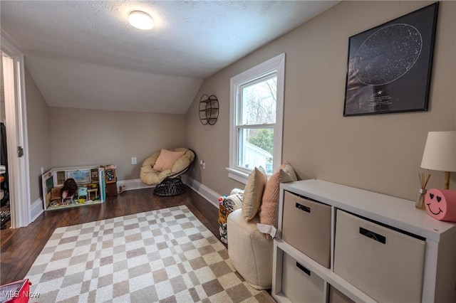 additional living space featuring dark hardwood / wood-style floors, vaulted ceiling, and a textured ceiling