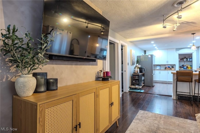 kitchen with rail lighting, a textured ceiling, stainless steel fridge, and dark hardwood / wood-style flooring