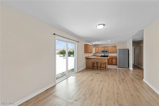 kitchen with sink, light hardwood / wood-style floors, kitchen peninsula, and appliances with stainless steel finishes