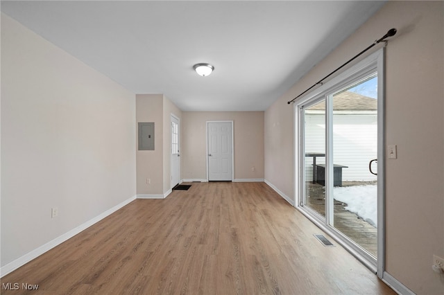 unfurnished room featuring electric panel and light hardwood / wood-style floors