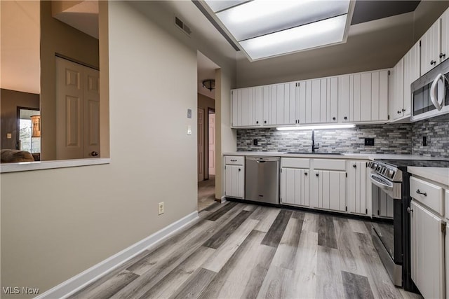 4539 Saint James Cir NW, Canton, OH 44708 - kitchen with appliances with stainless steel finishes, tasteful backsplash, white cabinetry, sink, and light hardwood / wood-style floors