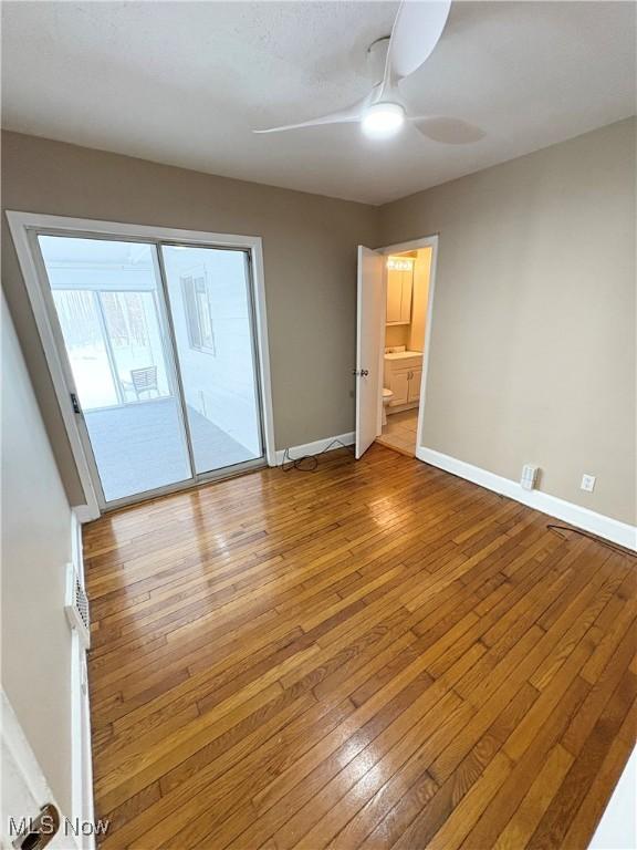 unfurnished bedroom with light hardwood / wood-style flooring, ensuite bath, access to outside, and ceiling fan