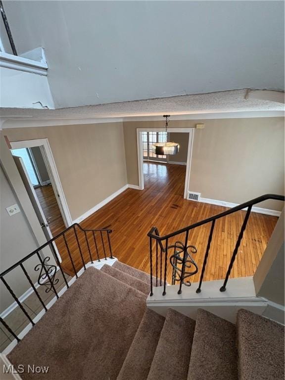 stairway featuring wood-type flooring and an inviting chandelier