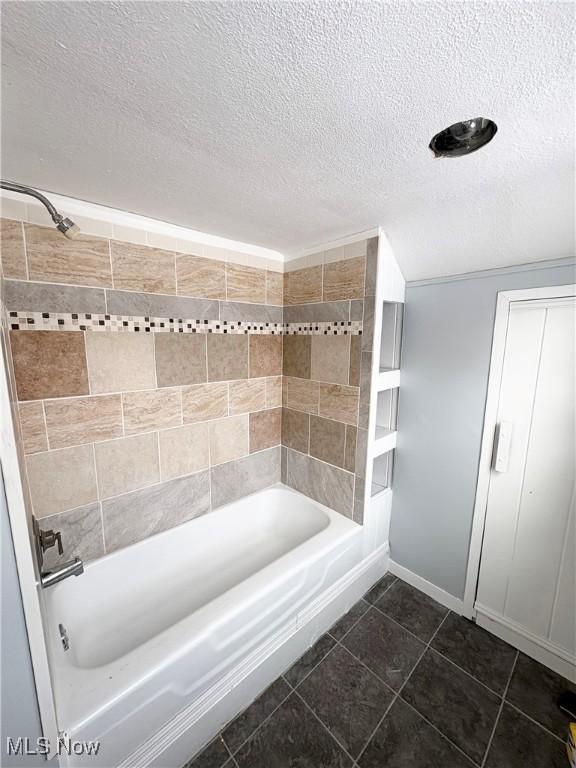 bathroom featuring tile patterned flooring, tiled shower / bath, and a textured ceiling