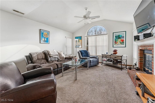 living room featuring ceiling fan, a fireplace, vaulted ceiling, and carpet