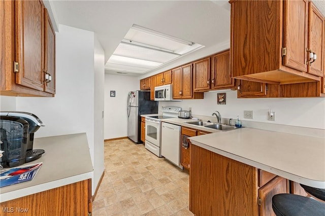 kitchen with white appliances, a breakfast bar, sink, and kitchen peninsula