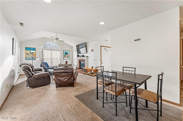 dining space featuring ceiling fan, carpet flooring, vaulted ceiling, and a textured ceiling