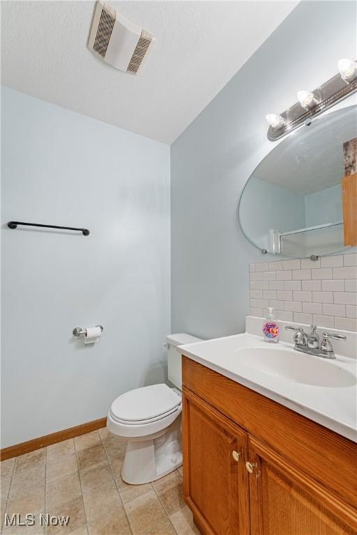 bathroom featuring vanity, backsplash, and toilet