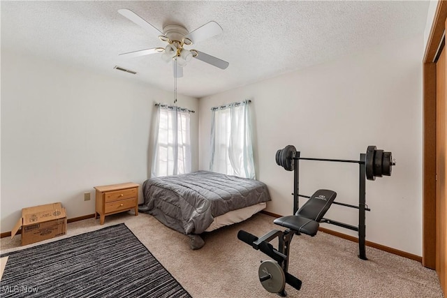 carpeted bedroom with ceiling fan and a textured ceiling