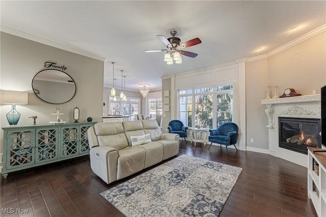 living room with ceiling fan with notable chandelier, dark wood-type flooring, and ornamental molding