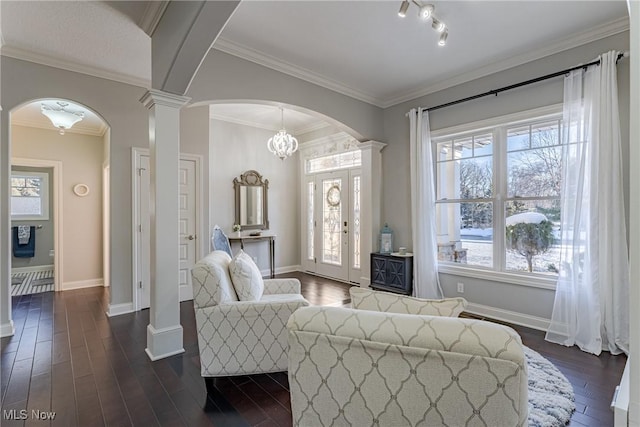 living room with decorative columns, a healthy amount of sunlight, dark wood-type flooring, and crown molding