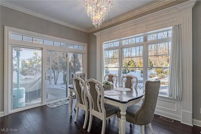 dining room with an inviting chandelier, dark hardwood / wood-style flooring, ornamental molding, and a healthy amount of sunlight