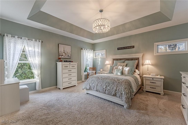 bedroom with a notable chandelier, a tray ceiling, and light colored carpet