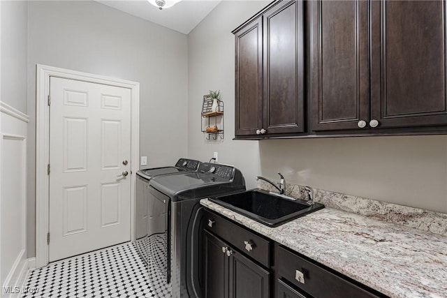 clothes washing area featuring cabinets, sink, and washing machine and dryer