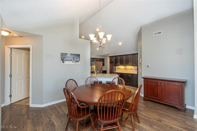 dining room with an inviting chandelier, dark hardwood / wood-style flooring, and vaulted ceiling