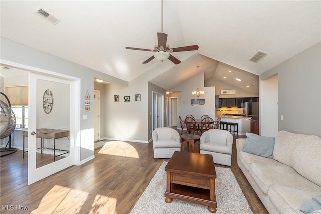 living room featuring lofted ceiling, ceiling fan with notable chandelier, and wood-type flooring