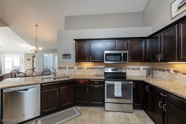 kitchen with appliances with stainless steel finishes, decorative light fixtures, sink, light stone counters, and kitchen peninsula