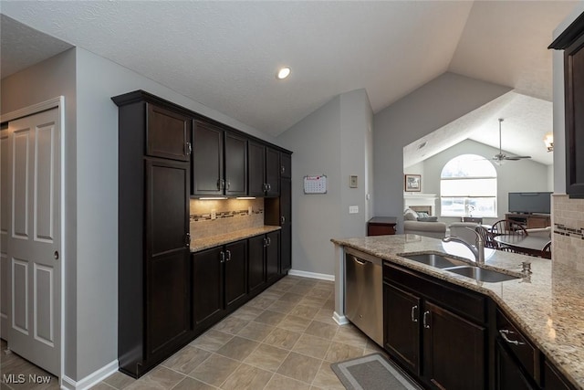 kitchen featuring sink, light stone counters, dark brown cabinetry, vaulted ceiling, and stainless steel dishwasher