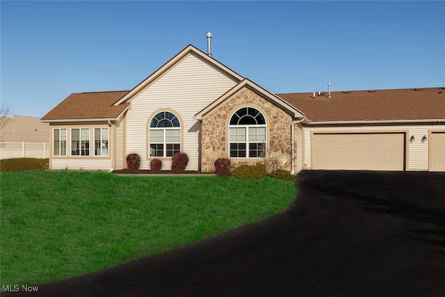 view of front of house with driveway, stone siding, an attached garage, and a front lawn