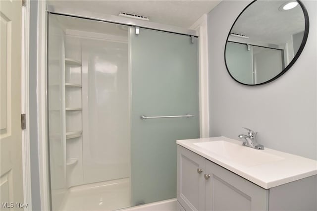 bathroom featuring vanity and a shower with door