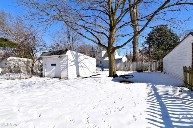 yard layered in snow with a garage and an outbuilding