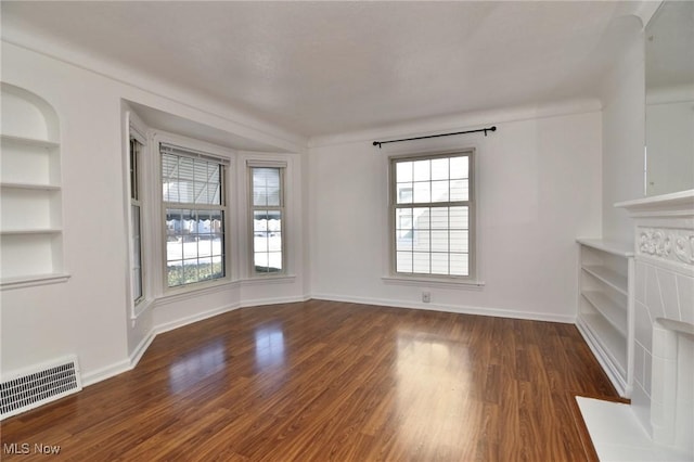 unfurnished living room with built in shelves and dark hardwood / wood-style floors