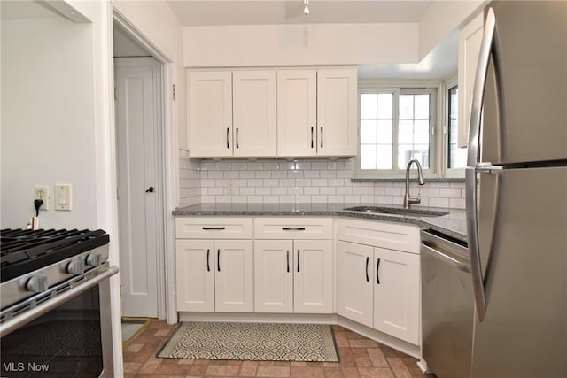 kitchen featuring white cabinetry, sink, stainless steel appliances, and dark stone counters