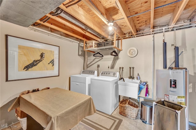 washroom featuring electric water heater, sink, and independent washer and dryer